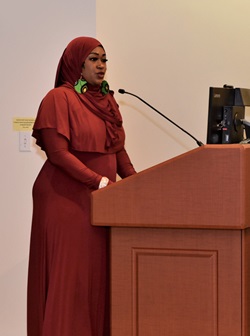 Patient care technician Jamillah Muhammad stands behind a podium on the Pennsylvania Hospital Zubrow Auditorium stage 